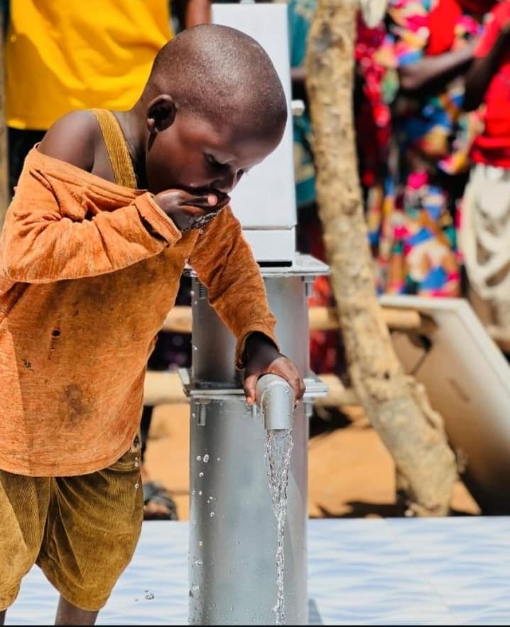 A young boy drinking clean water from a Musana-built water point